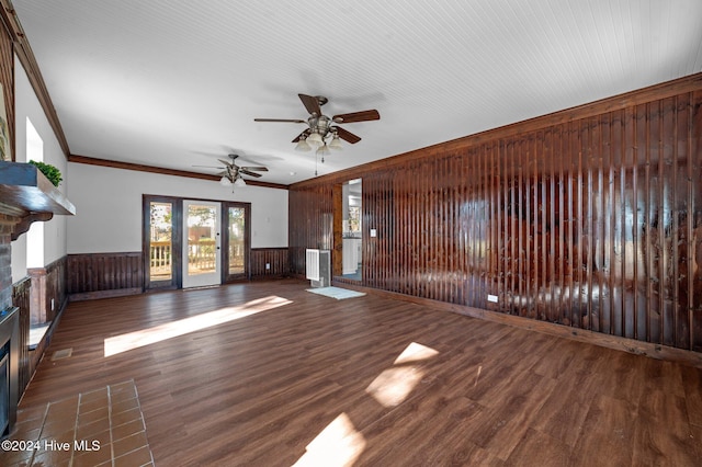 unfurnished living room with ornamental molding, ceiling fan, dark wood-type flooring, and wood walls