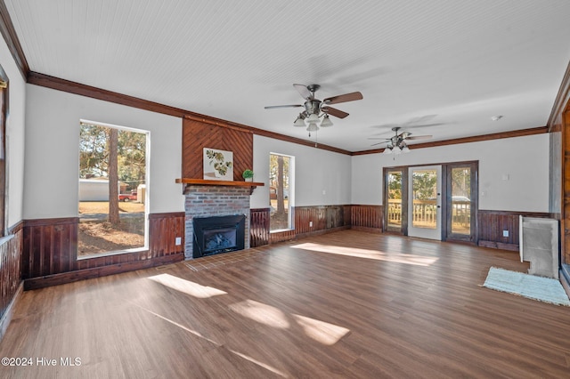 unfurnished living room with hardwood / wood-style floors, a fireplace, wood walls, and crown molding