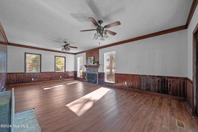 unfurnished living room with hardwood / wood-style floors, a brick fireplace, crown molding, and wood walls