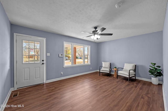 sitting room featuring dark hardwood / wood-style floors, ceiling fan, and a textured ceiling