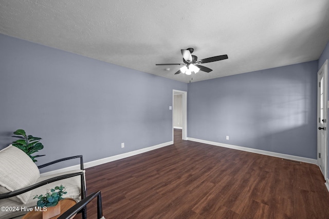 empty room with dark hardwood / wood-style floors, ceiling fan, and a textured ceiling