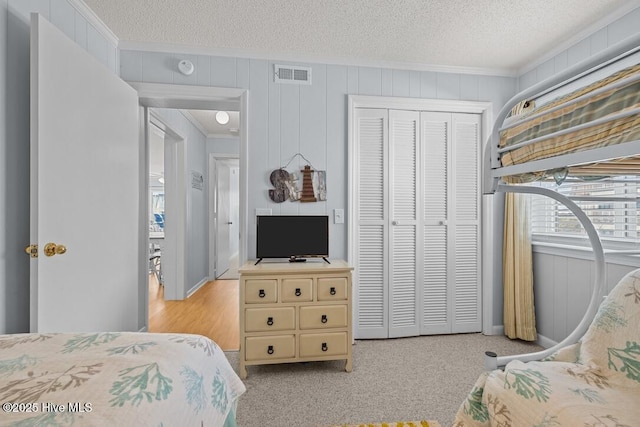 bedroom with ornamental molding, light colored carpet, a textured ceiling, and a closet