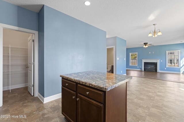 kitchen featuring a textured ceiling, a center island, pendant lighting, and ceiling fan with notable chandelier