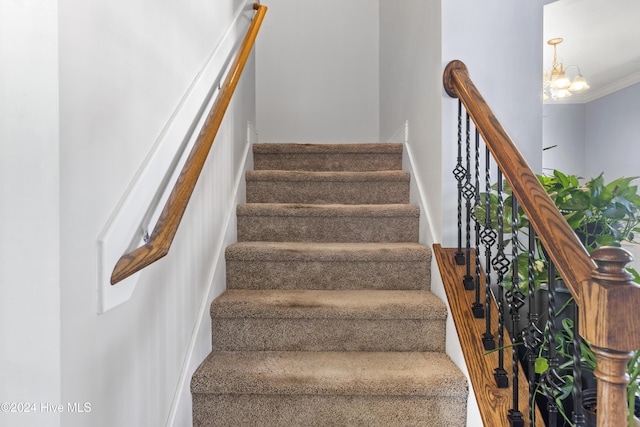 staircase featuring a chandelier and ornamental molding