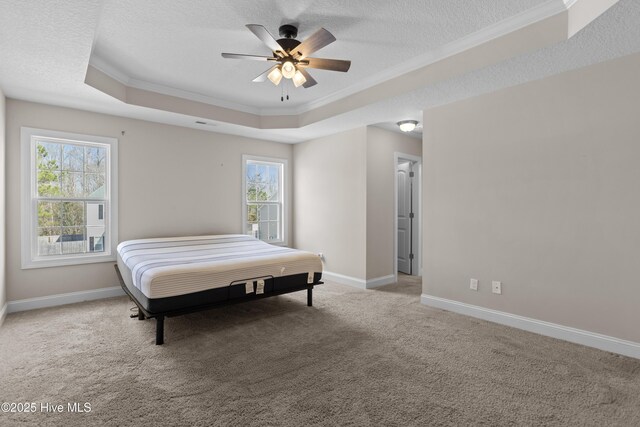 carpeted bedroom with a textured ceiling, a tray ceiling, ceiling fan, and crown molding