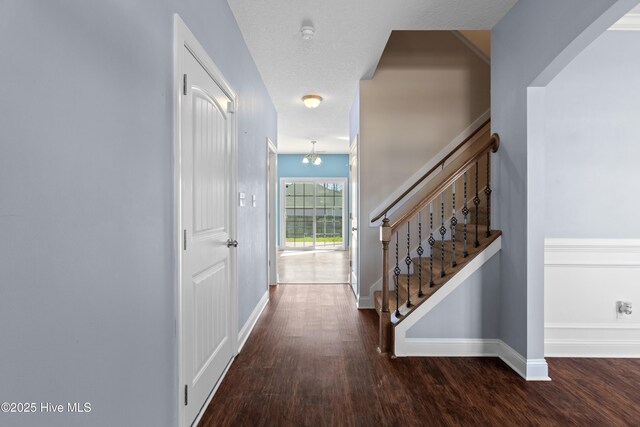 hall featuring dark hardwood / wood-style floors, a textured ceiling, and a chandelier