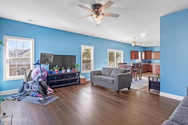 living room with a textured ceiling, ceiling fan, and dark hardwood / wood-style floors