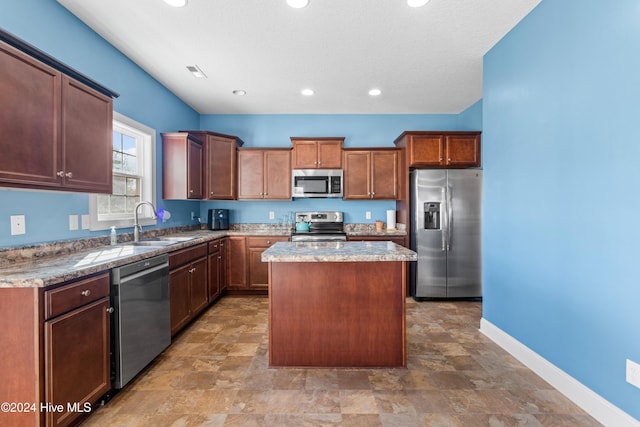 kitchen featuring appliances with stainless steel finishes, a center island, a textured ceiling, and sink