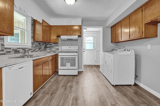 kitchen featuring white appliances, sink, light wood-type flooring, extractor fan, and washing machine and clothes dryer