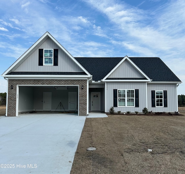 view of front facade with roof with shingles, driveway, and brick siding