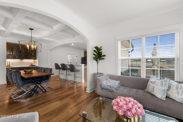 living room with coffered ceiling, a chandelier, ornamental molding, beam ceiling, and dark wood-type flooring