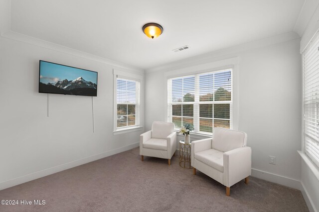 living area with crown molding and carpet