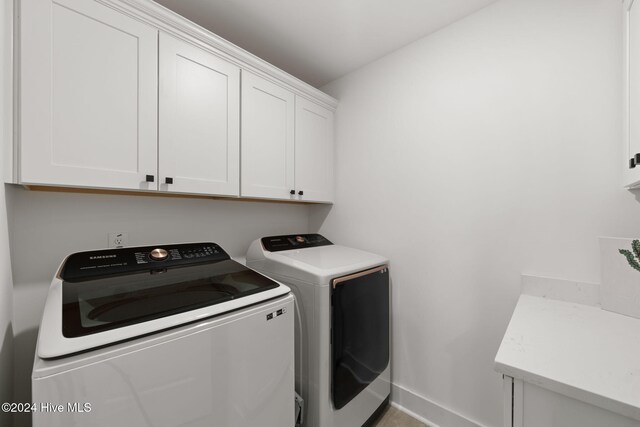 clothes washing area featuring washer and dryer and cabinets