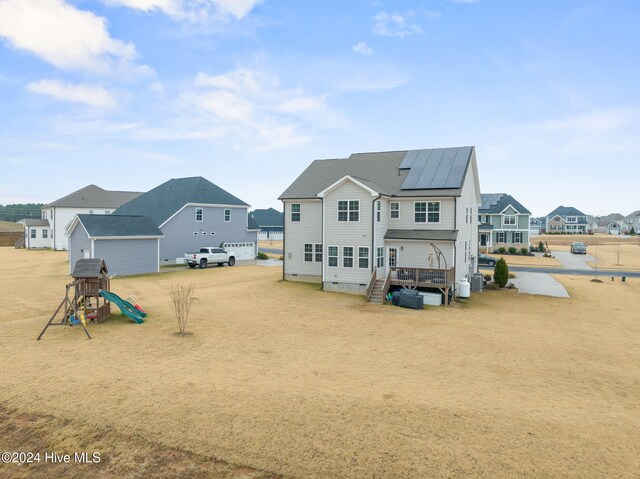 back of property featuring a playground and solar panels