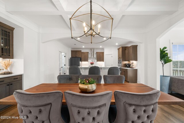 dining area featuring a notable chandelier, coffered ceiling, beam ceiling, and wood-type flooring