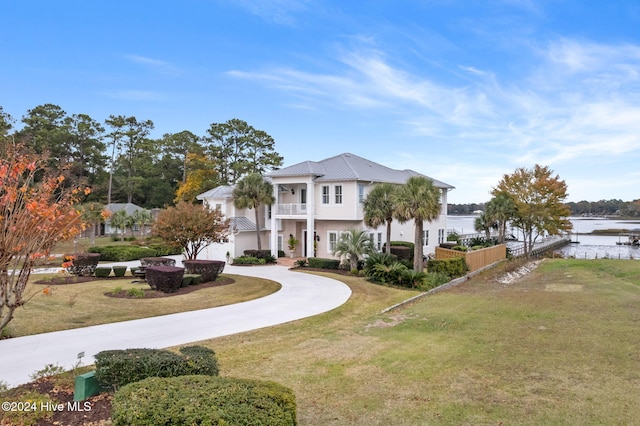 view of front facade with a water view, a front lawn, and a balcony