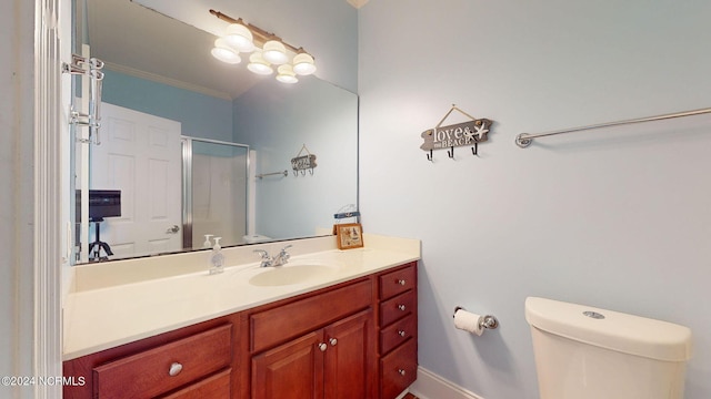 bathroom featuring vanity, toilet, ornamental molding, and a shower with door