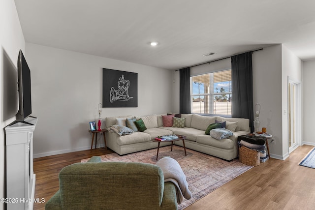 living room featuring wood finished floors, visible vents, and baseboards