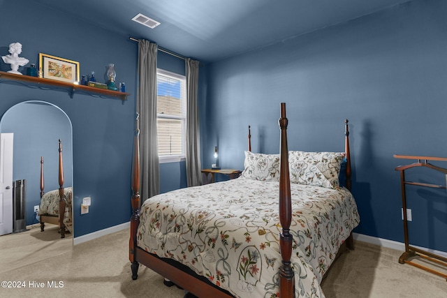 bedroom with arched walkways, carpet flooring, visible vents, and baseboards