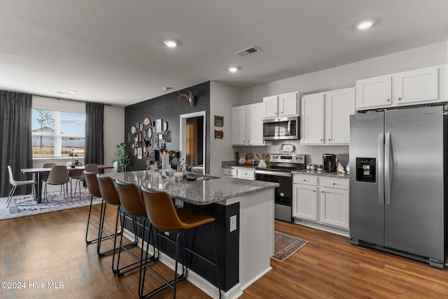 kitchen featuring a breakfast bar area, stainless steel appliances, dark wood-style flooring, a sink, and white cabinetry