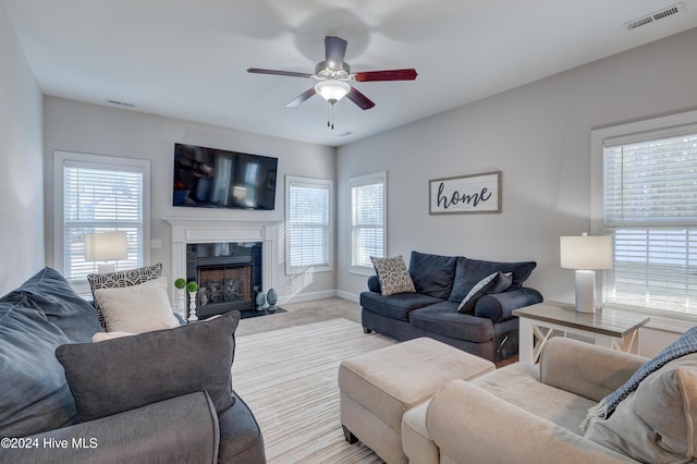 living room featuring a wealth of natural light, ceiling fan, light carpet, and a high end fireplace