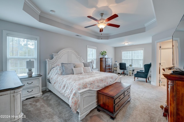 bedroom with ceiling fan, light colored carpet, and a tray ceiling