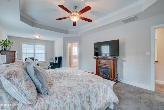 carpeted bedroom with a tray ceiling, ceiling fan, and crown molding