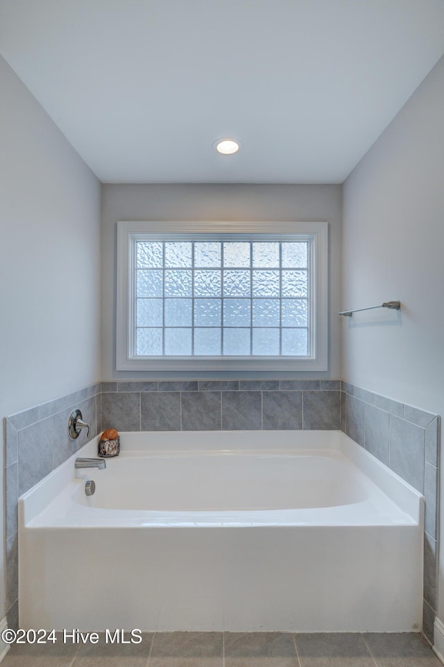 bathroom with tile patterned floors, a bath, and a wealth of natural light