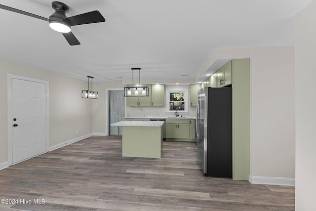 kitchen with sink, green cabinets, decorative light fixtures, a kitchen island, and appliances with stainless steel finishes