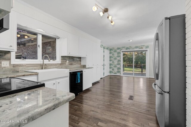 kitchen featuring stainless steel refrigerator, light stone countertops, white cabinets, and black dishwasher