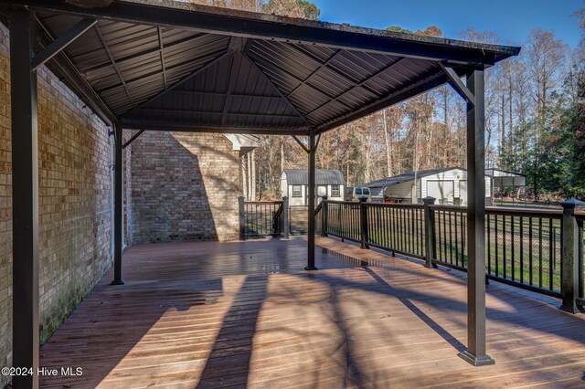 wooden deck featuring a gazebo and a storage unit