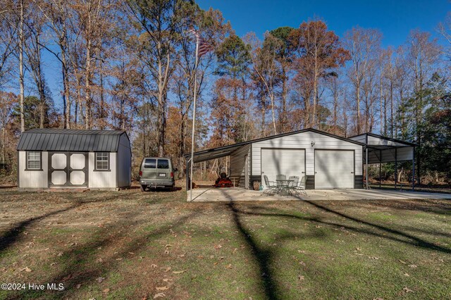 view of outdoor structure featuring a garage, a carport, and a lawn