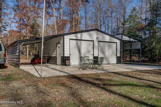 view of outdoor structure featuring a garage, a carport, and a lawn