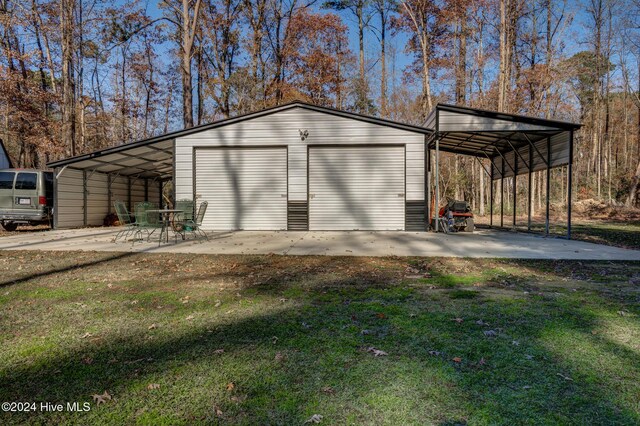 view of outdoor structure with a carport, a garage, and a lawn