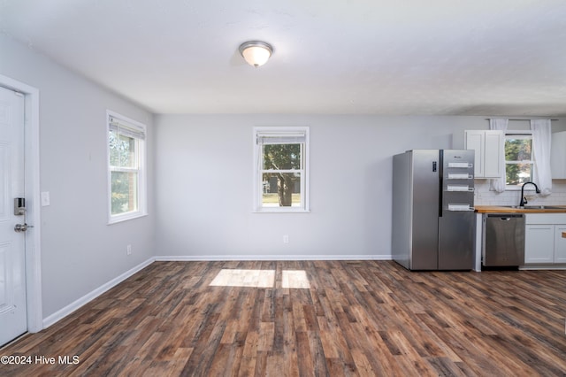 kitchen featuring stainless steel appliances, white cabinetry, plenty of natural light, and dark hardwood / wood-style floors