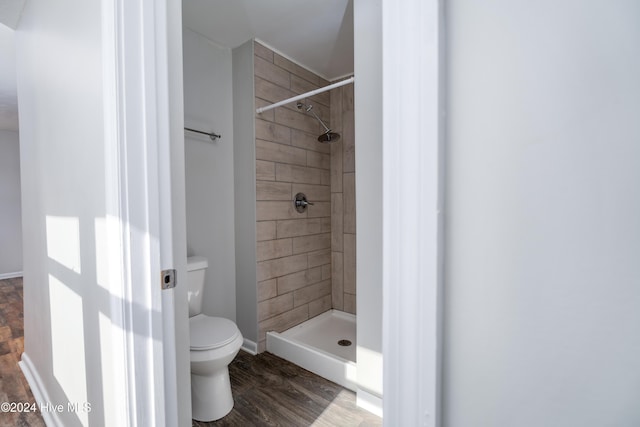 bathroom featuring tiled shower, wood-type flooring, and toilet