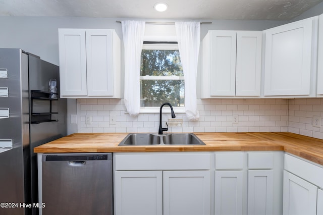 kitchen with butcher block countertops, white cabinetry, sink, and stainless steel appliances