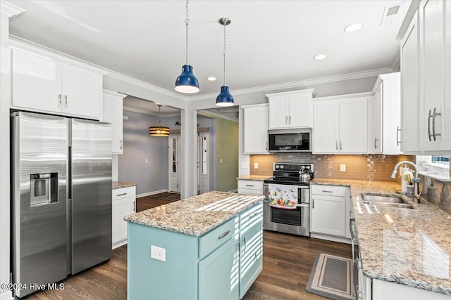 kitchen with a kitchen island, appliances with stainless steel finishes, white cabinets, and decorative light fixtures