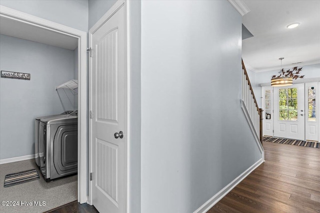 clothes washing area with ornamental molding, dark wood-type flooring, and washing machine and clothes dryer