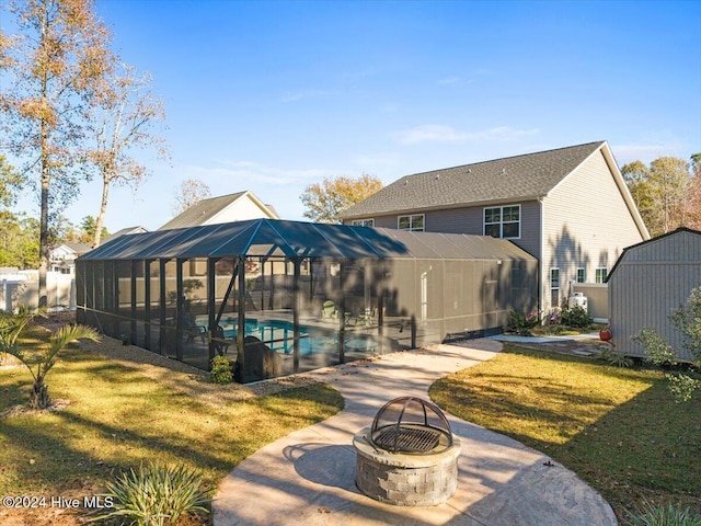 rear view of property with a lanai, a fire pit, and a lawn