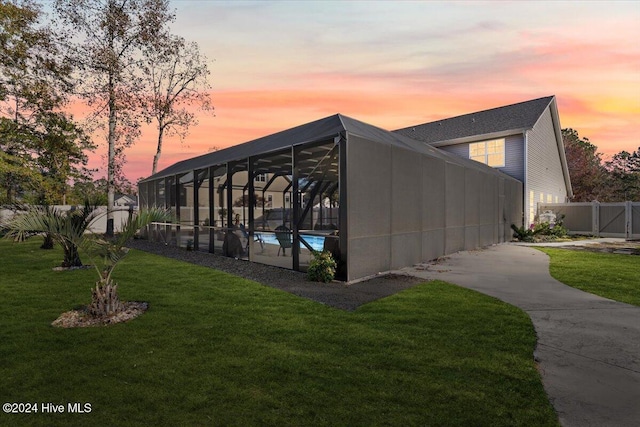 property exterior at dusk featuring a fenced in pool, a yard, and glass enclosure