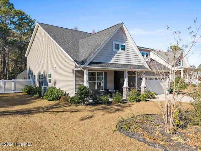 craftsman inspired home with a porch, a garage, a front yard, and central air condition unit