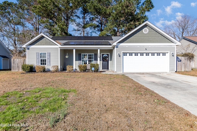 ranch-style house with solar panels, a porch, and a garage