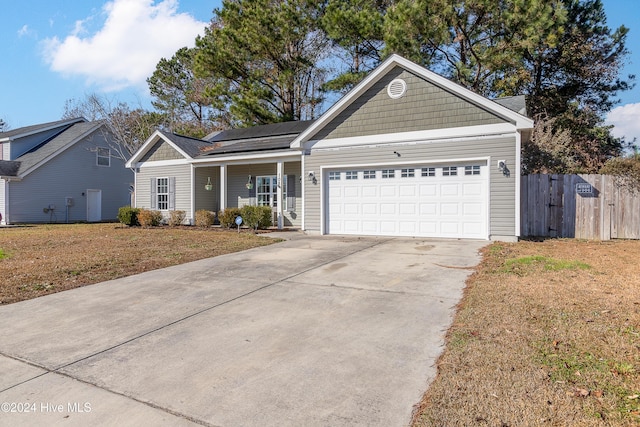 view of front of house featuring covered porch, a garage, and solar panels