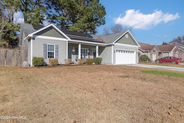 view of front of property featuring solar panels, a porch, a garage, and a front yard