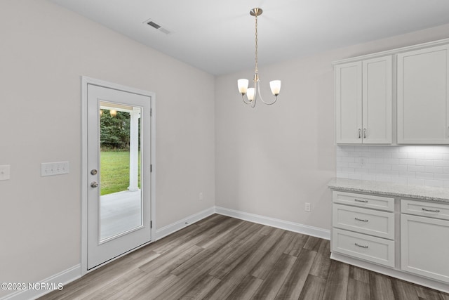 unfurnished dining area with hardwood / wood-style floors and a chandelier