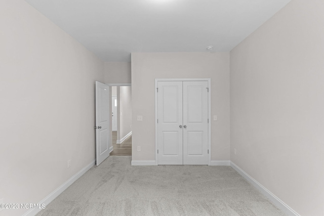 unfurnished bedroom with light carpet and a closet