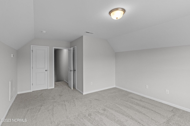 additional living space featuring light carpet and vaulted ceiling