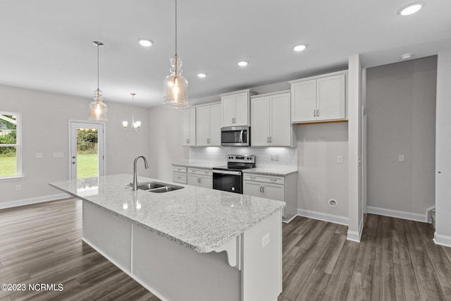 kitchen featuring white cabinetry, sink, decorative light fixtures, a center island with sink, and appliances with stainless steel finishes