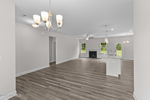 unfurnished living room featuring dark hardwood / wood-style flooring, ceiling fan with notable chandelier, and sink